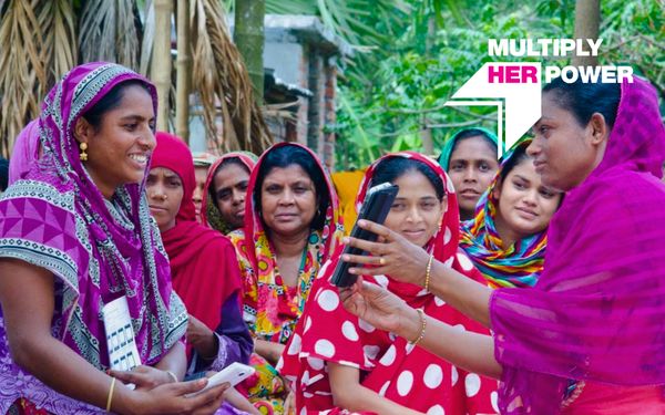 Image of a microfinance borrower group in Bangladesh with "Multiply Her Power" graphic overlay