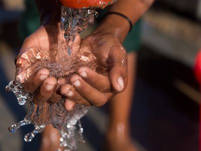 A close up of hands catching clean water from a spout
