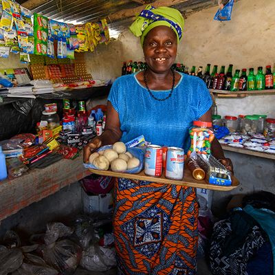 Kumba, a participant of BRAC's Graduation programme in Liberia, smiles in her shop while she holds up a tray of her products