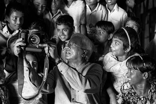 Sir Fazle Hasan Abed shows a group of children images taken on a camera