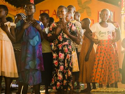 Children standing with their hands over their hearts indoors.