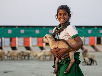 A girl holds a goat in Bangladesh