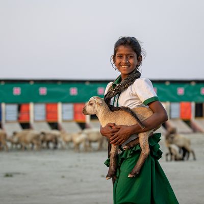 A girl holds a goat in Bangladesh