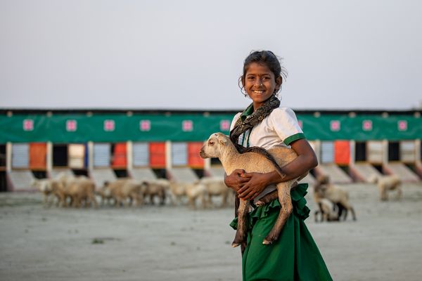 A girl holds a goat in Bangladesh