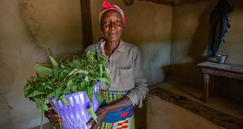 Lucy holds a bundle of produce from her kitchen garden while in her home
