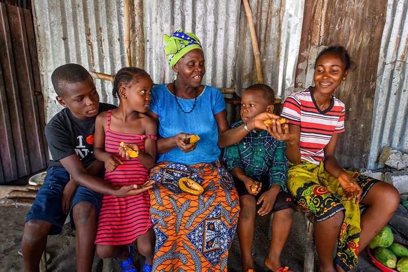 Photo by Alison Wright. A grandmother, who is a participant in BRAC's Ultra-Poor Graduation program, slices and shares a papaya with her four grandchildren.