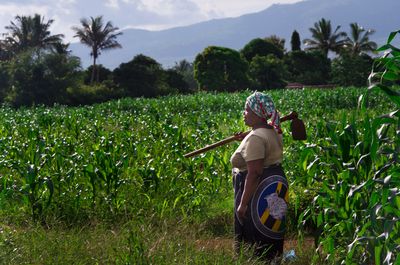 Woman standing in field with shovel over her shoulder