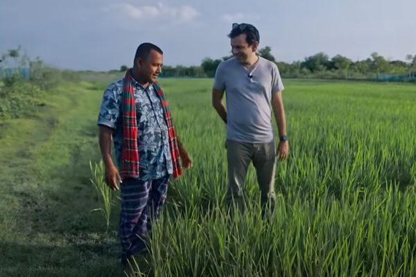 Asif Saleh stands with Mustakim bhai, a farmer, while learning about green paddy fields