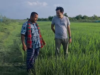 Asif Saleh stands with Mustakim bhai, a farmer, while learning about green paddy fields