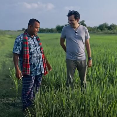 Asif Saleh stands with Mustakim bhai, a farmer, while learning about green paddy fields