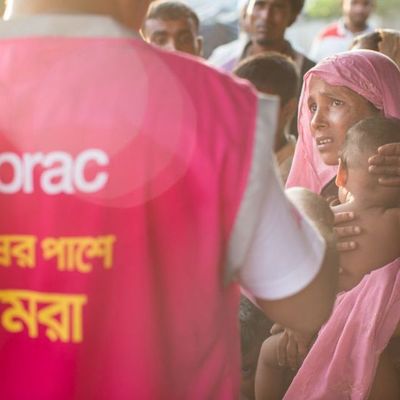 A BRAC staff member speaks to a small group of Rohingya