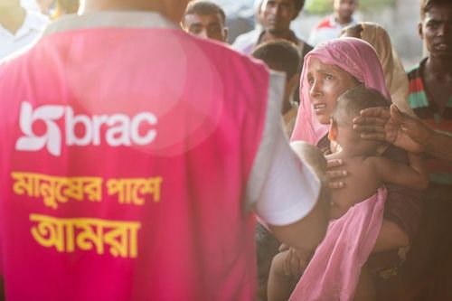 A BRAC staff member speaks to a small group of Rohingya