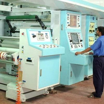 A man in dark pants and a light blue tshirt works at a printing machine