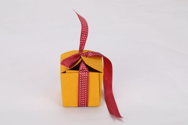 A decorative yellow gift box is adorned with a red and white polka dot ribbon