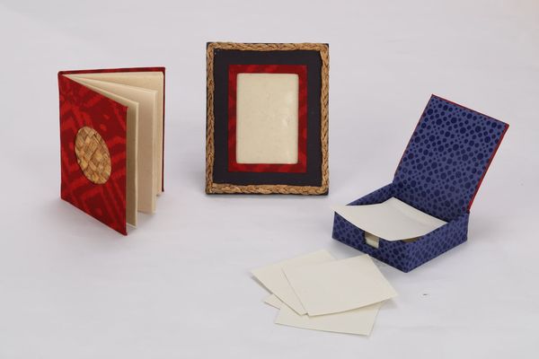 A selection of gift items made of recycled paper is shown including a photo frame and a notebook