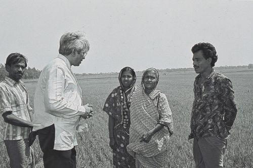 An old black and white photo shows BRAC Founder Fazle Hasan Abed talking to villagers in Bangladesh.