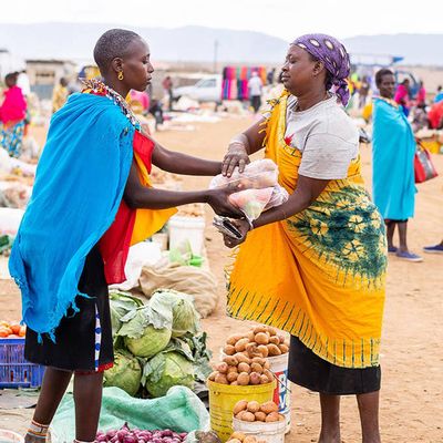 Two women exchange goods in a market.