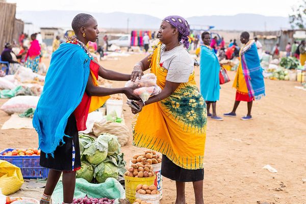 Two women exchange goods in a market.