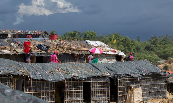 BRAC Staff walk amid shelters distributing nets to families