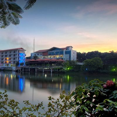A hotel space is illuminated at night with colorful lights that reflect off the water below