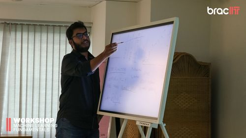 A man stands at a digital board and explains machine learning in a workshop