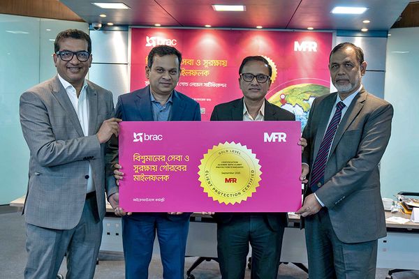 Four Bangladeshi men, including BRAC Executive Director Asif Saleh, stand together holding a pink board that showcases the gold award