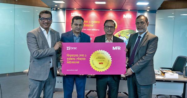 Four Bangladeshi men, including BRAC Executive Director Asif Saleh, stand together holding a pink board that showcases the gold award