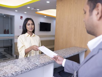 A woman speaks with a man at a reception desk