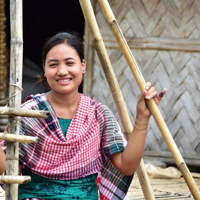 A woman in an apprentice program stands amid a bamboo frame