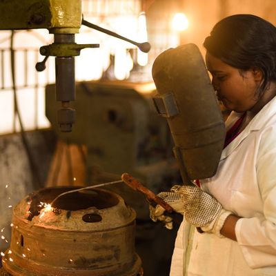 A woman looks through safety glass while welding