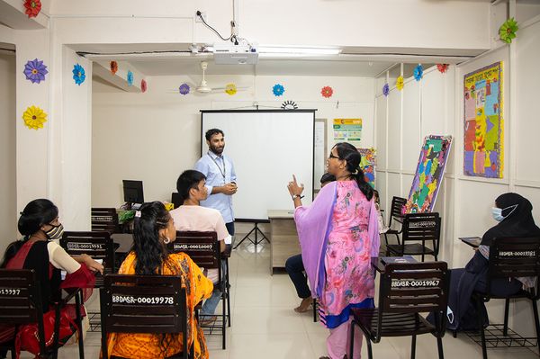 A young woman addresses her classmates during a retail sales classroom training