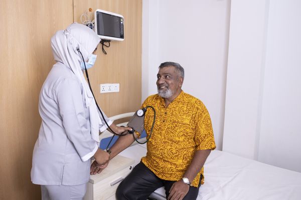 A doctor takes the blood pressure of a smiling patient