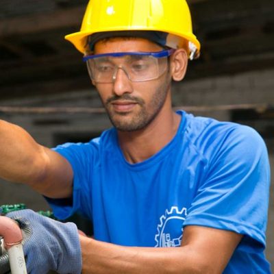 A man wearing a blue shirt and yellow hard hat works hard