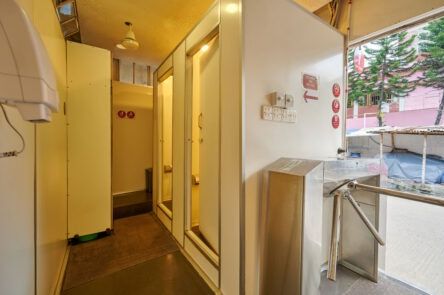 The image shows a bright clean bathroom entrance with a small turnstile at the door