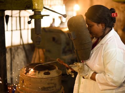 A woman looks through safety glass while welding