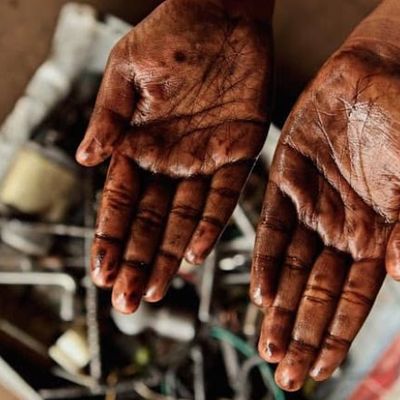 A woman shows her hands which are covered with machine oil