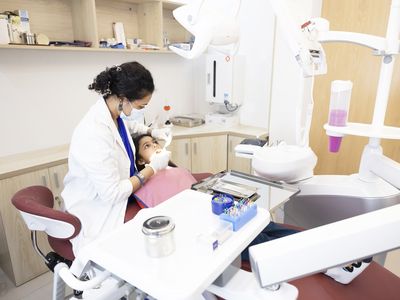 A dentist works with a young female patient
