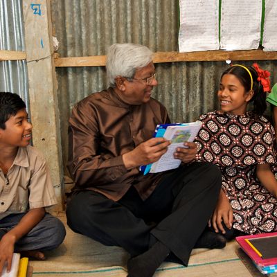 BRAC founder Sir Fazle Hasan Abed reads to a group of four children in a BRAC primary school in Bangladesh.