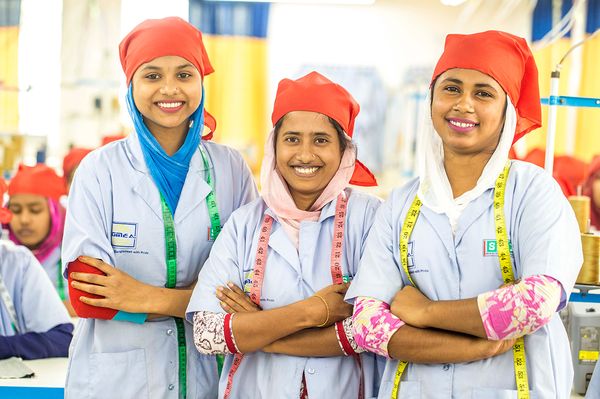 Three women stand together in a factory