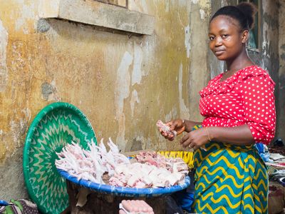 Woman Microfinance client in Liberia tends to her basket of processed chicken