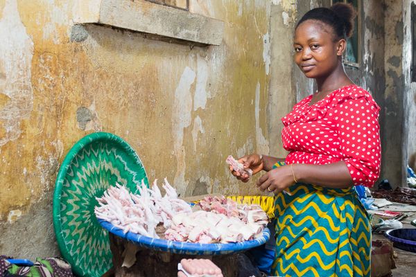 Woman Microfinance client in Liberia tends to her basket of processed chicken