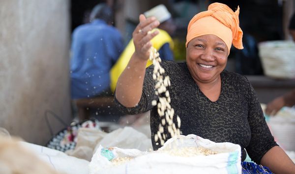 Smiling woman pouring grains from her hand into a sack.