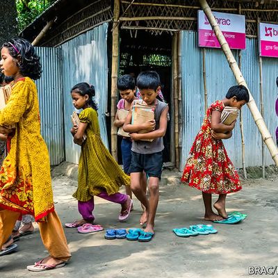 Children walk from a BRAC school holding their school books.