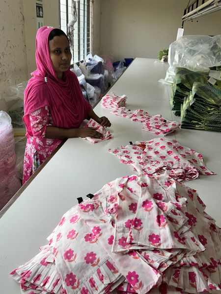 An artisan folds shirts handmade for sale at Aarong.