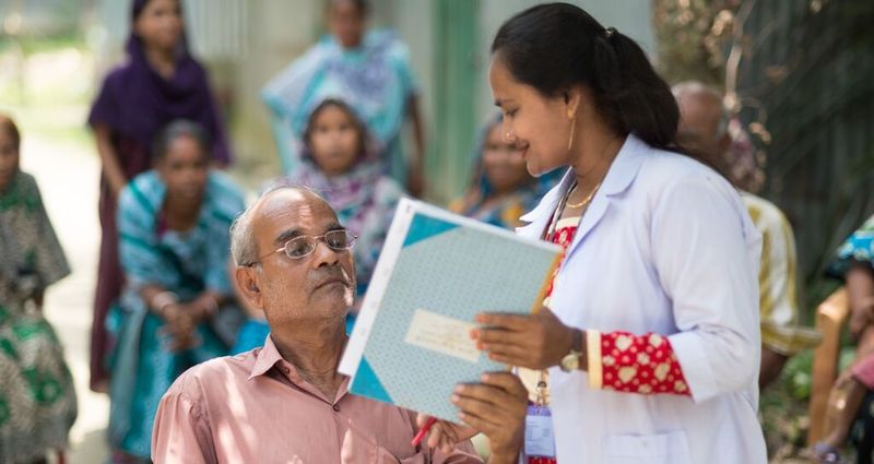 A woman in Bangladesh helps a man with his new eyeglasses. Photo from Vision Spring.