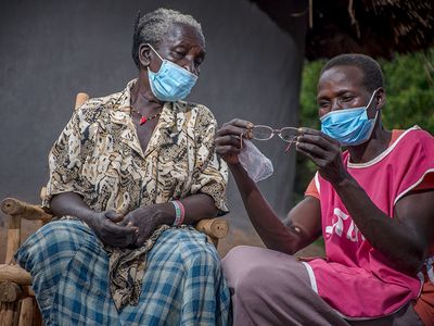 A health worker inspects a pair of glasses for a patient in Uganda.