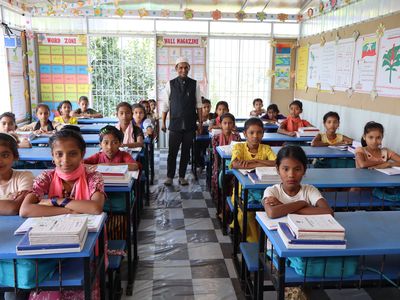 A Rohingya teacher stands at the back of a classroom of female students
