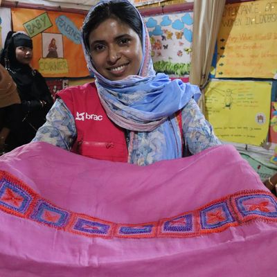 A BRAC employee holds a bright pink roll of fabric that Rohginya women have learned to decorate