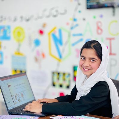 Smiling girl on a laptop at a school in Afghanistan