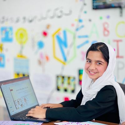Smiling girl on a laptop at a school in Afghanistan